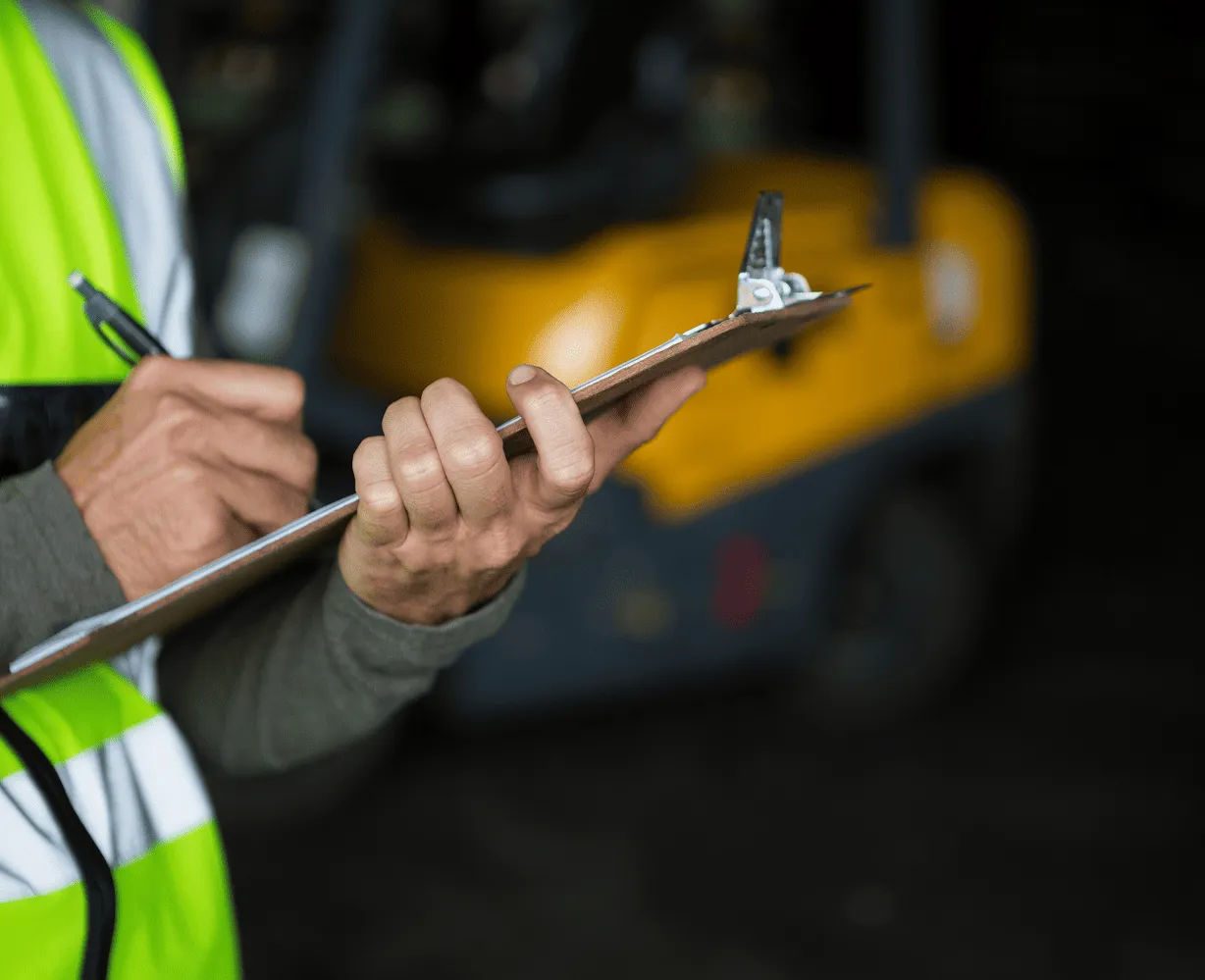Personne avec un gilet jaune en train d'écrire sur un document papier