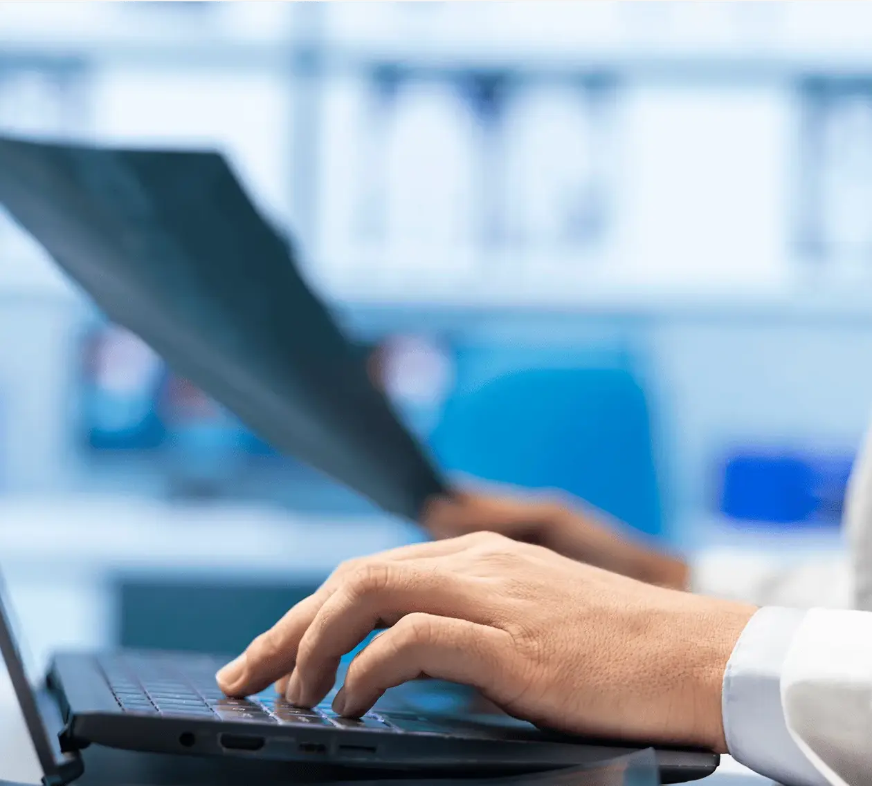 Personne en train d'écrire avec son clavier et avec un document à la main